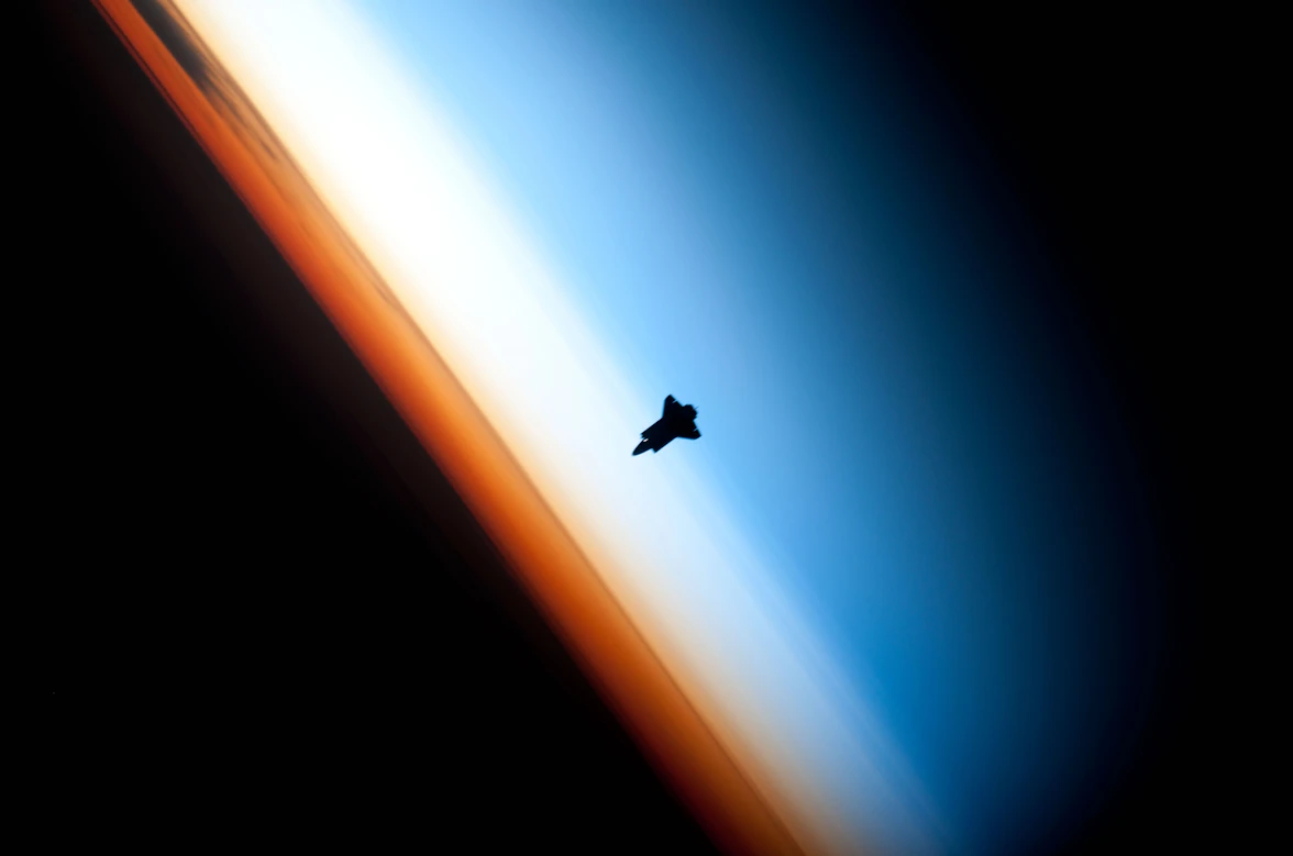 Silhouette d'une navette spatiale au-dessus de l'horizon terrestre